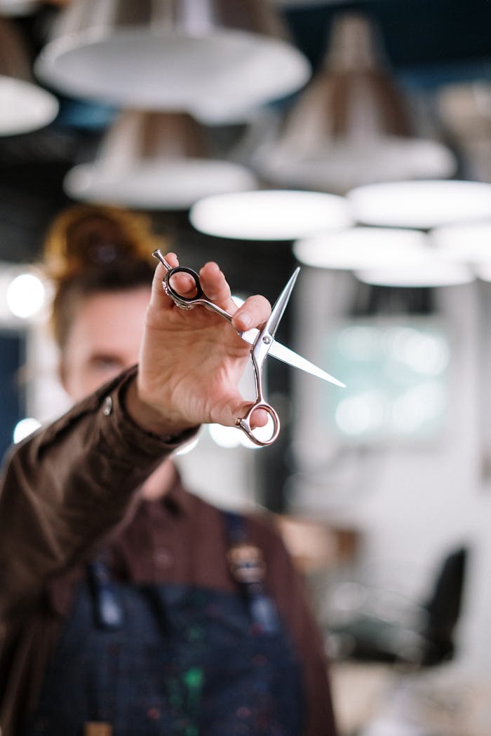 Close-up of a hairstylist holding scissors in a modern salon with blurred background.