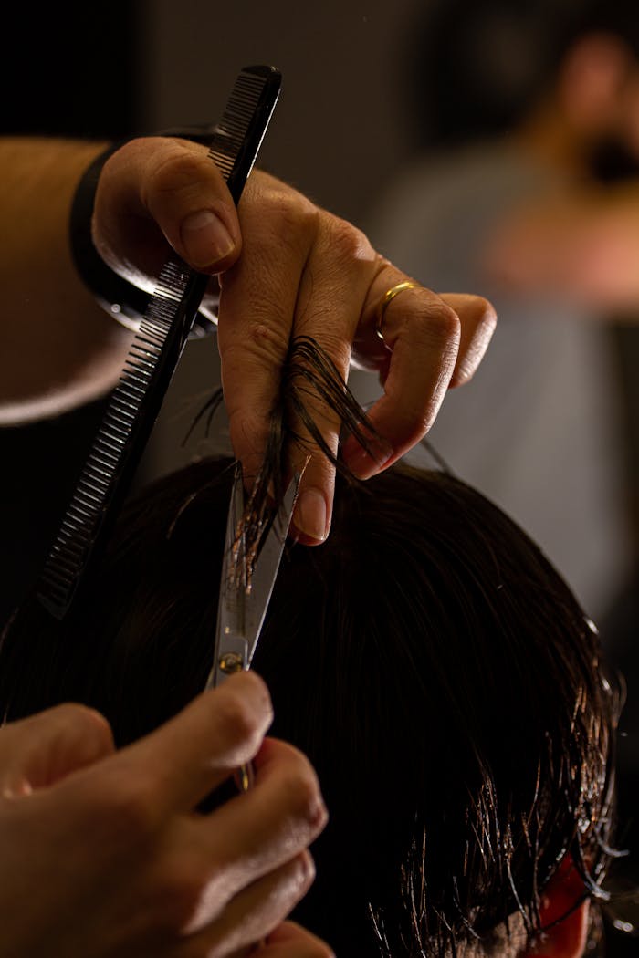Detailed shot of a barber cutting hair with scissors and comb, focusing on precision.